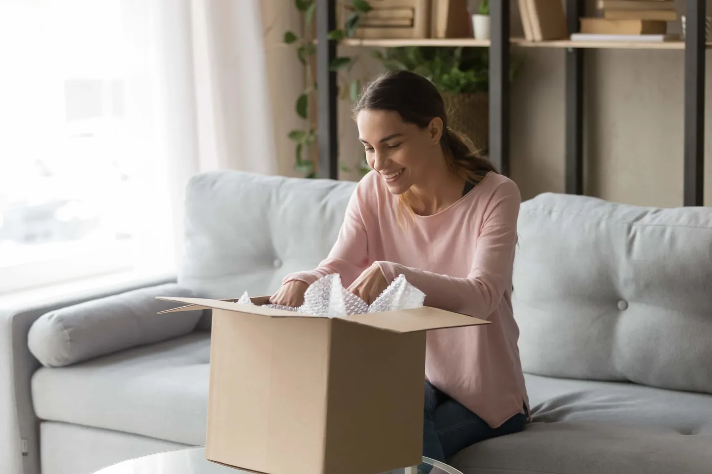 Smiling guest opening the parcel containing her lost item at home